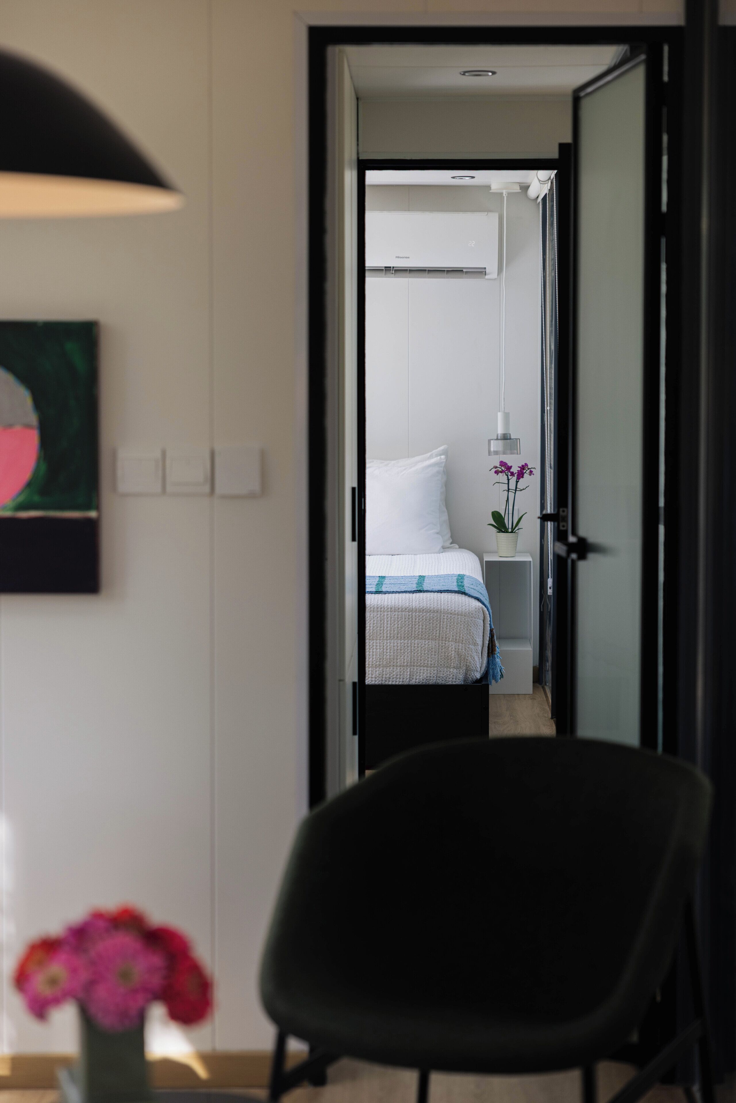 A hotel room with a bed, bedside table, and a chair.