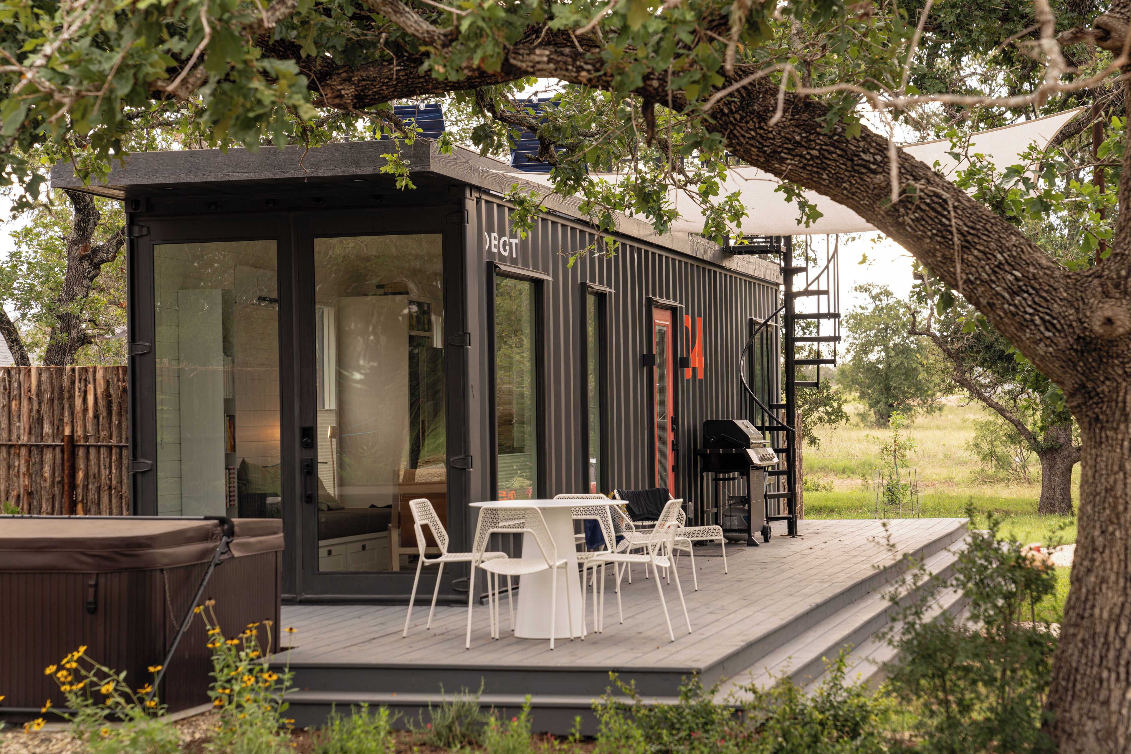 A modern outdoor deck with a dining area, a hot tub, and a covered seating area.