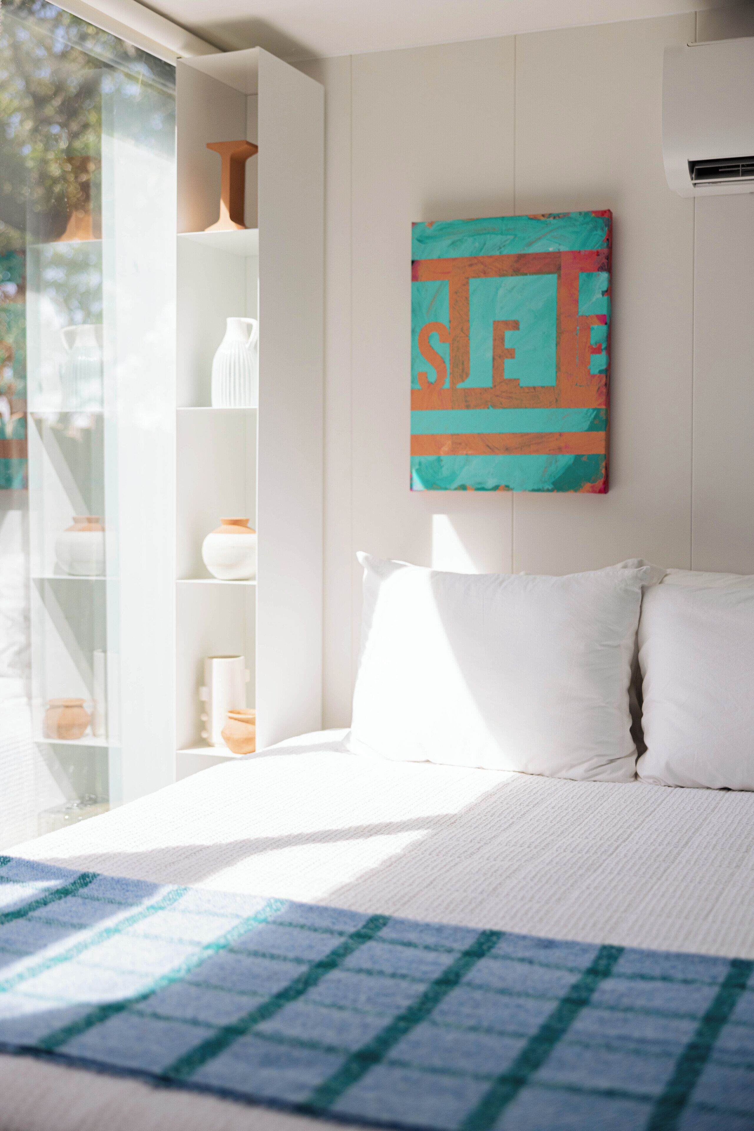 Ein Schlafzimmer mit Bett, Fenster und einer Ablage mit Dekoration.