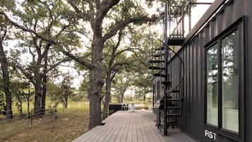 A modern building with a wooden deck, a spiral staircase, and large windows.