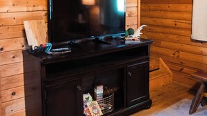 A wooden-paneled room with a flat-screen TV on a dark wooden cabinet. - 2 Lakeside : Charming 2-bedroom cabin with AC, WiFi in welcoming Solgohachia (Solgohachia)