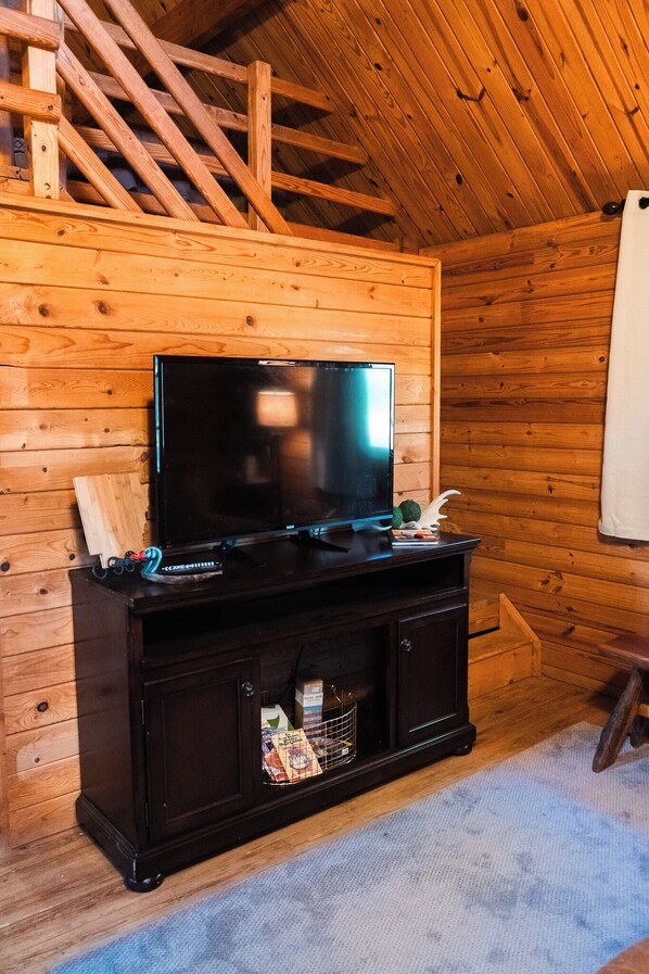 A wooden-paneled room with a flat-screen TV on a dark wooden cabinet. - 2 Lakeside : Charming 2-bedroom cabin with AC, WiFi in welcoming Solgohachia (Solgohachia)