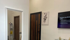 Una sala de estar moderna con un espejo grande, una mesa de centro de vidrio y un tapete gris.