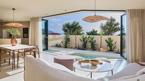 Ein modernes Wohnzimmer mit Pool, Essbereich und großen Fenstern.
