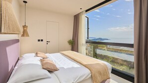 Ein modernes Schlafzimmer mit einem großen Bett, Meerblick und einem Balkon.