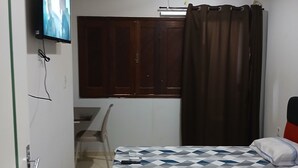 Une chambre à coucher comprenant un lit, un bureau, une chaise, un téléviseur et un appareil de climatisation.