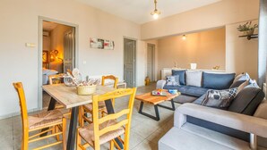 Uma sala de estar moderna com sofá, mesa de centro e área de jantar com cadeiras e mesa.