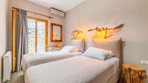 Quarto com duas camas, espelho, ar condicionado e um toco de árvore de madeira.