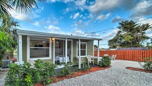 A single-story house with a covered porch, a gravel driveway, and a fenced backyard.