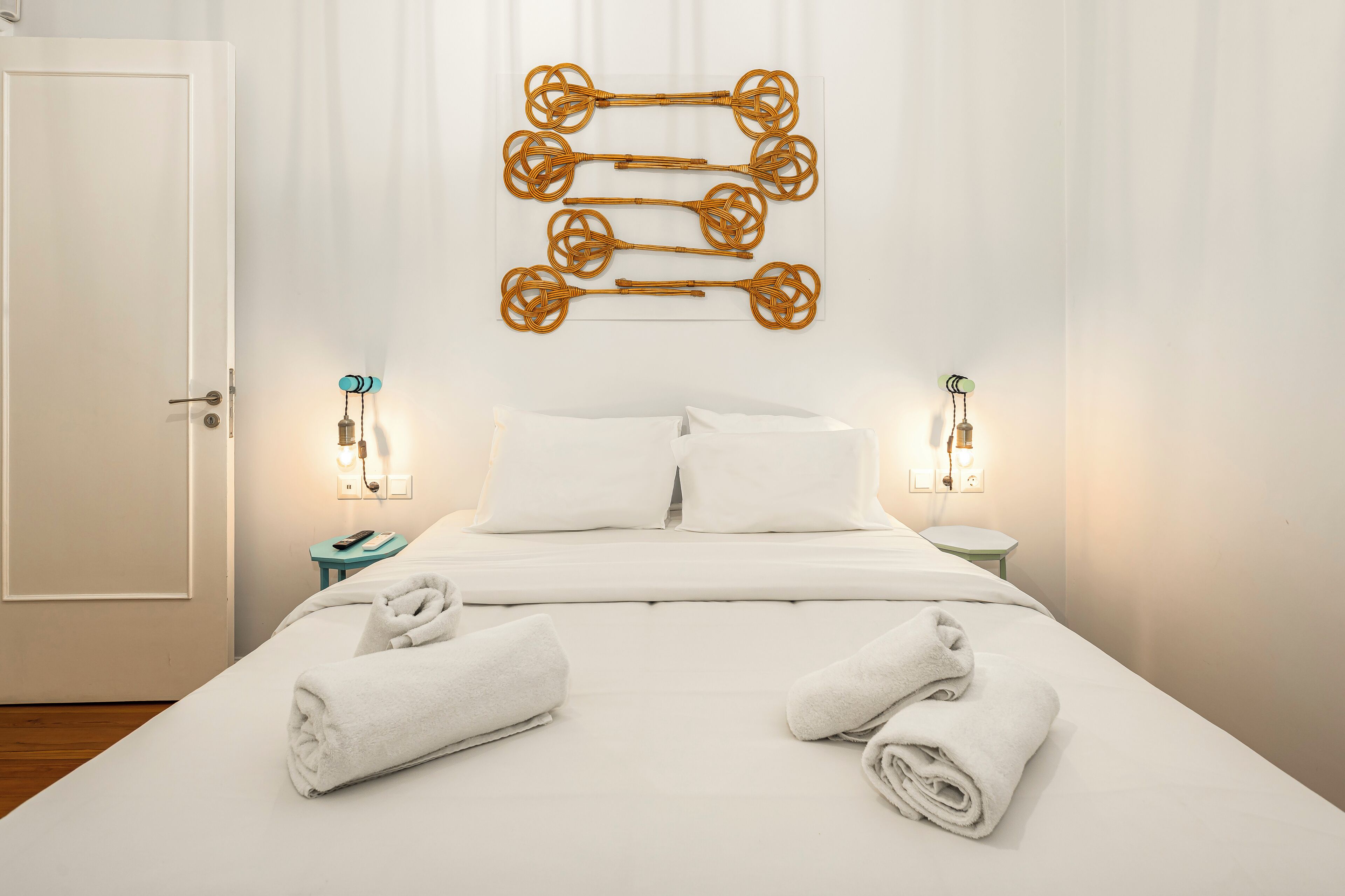 A hotel room with a neatly made bed, two bedside tables with lamps, and a wall-mounted light fixture.