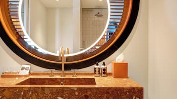 A bathroom with a round mirror, a sink, and a towel rack.