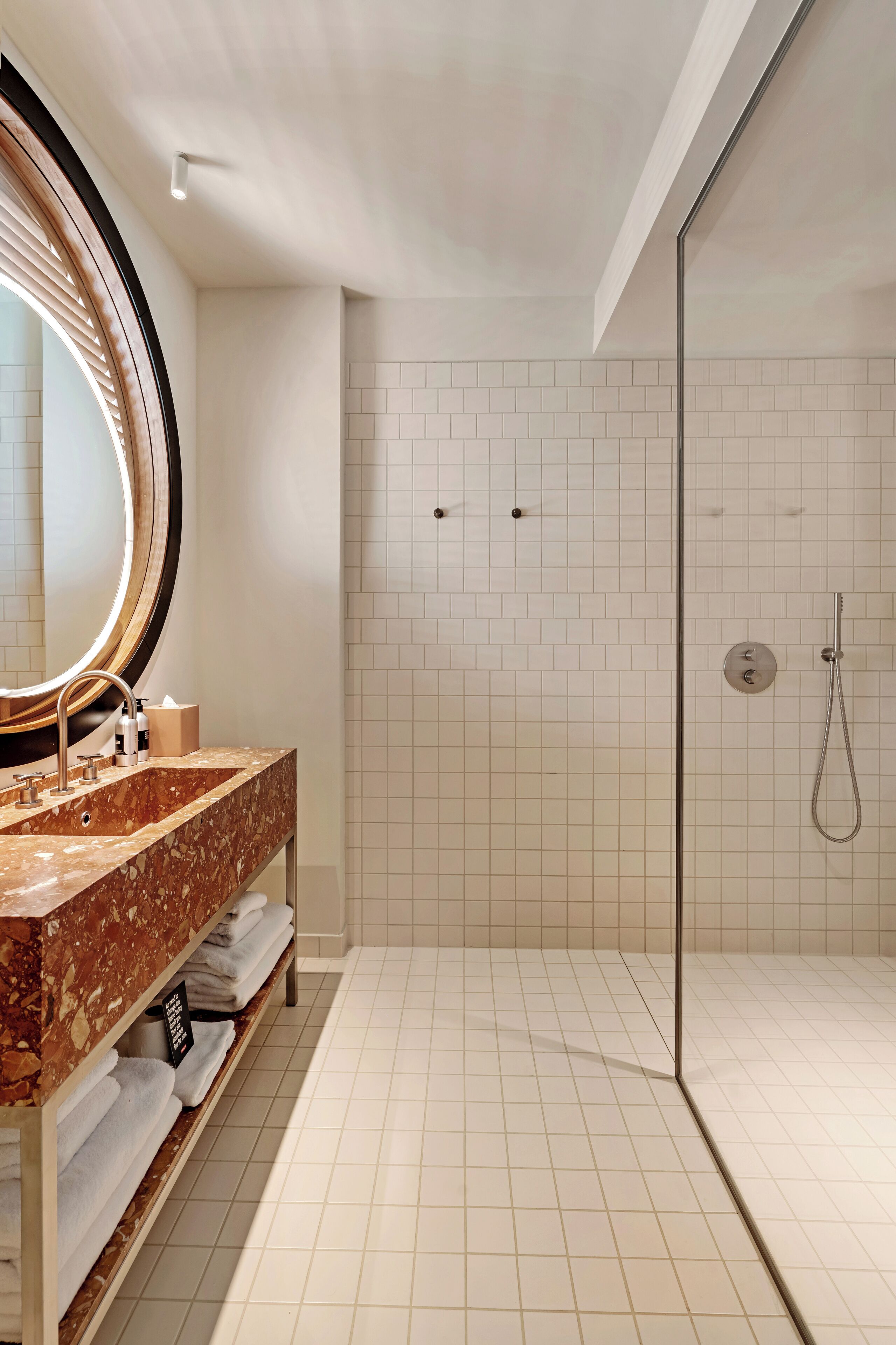 A modern bathroom with a marble sink, a large mirror, and a glass-enclosed shower.