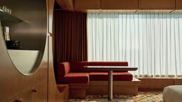 A modern room with a red sofa, a small table, and a large window with sheer curtains.