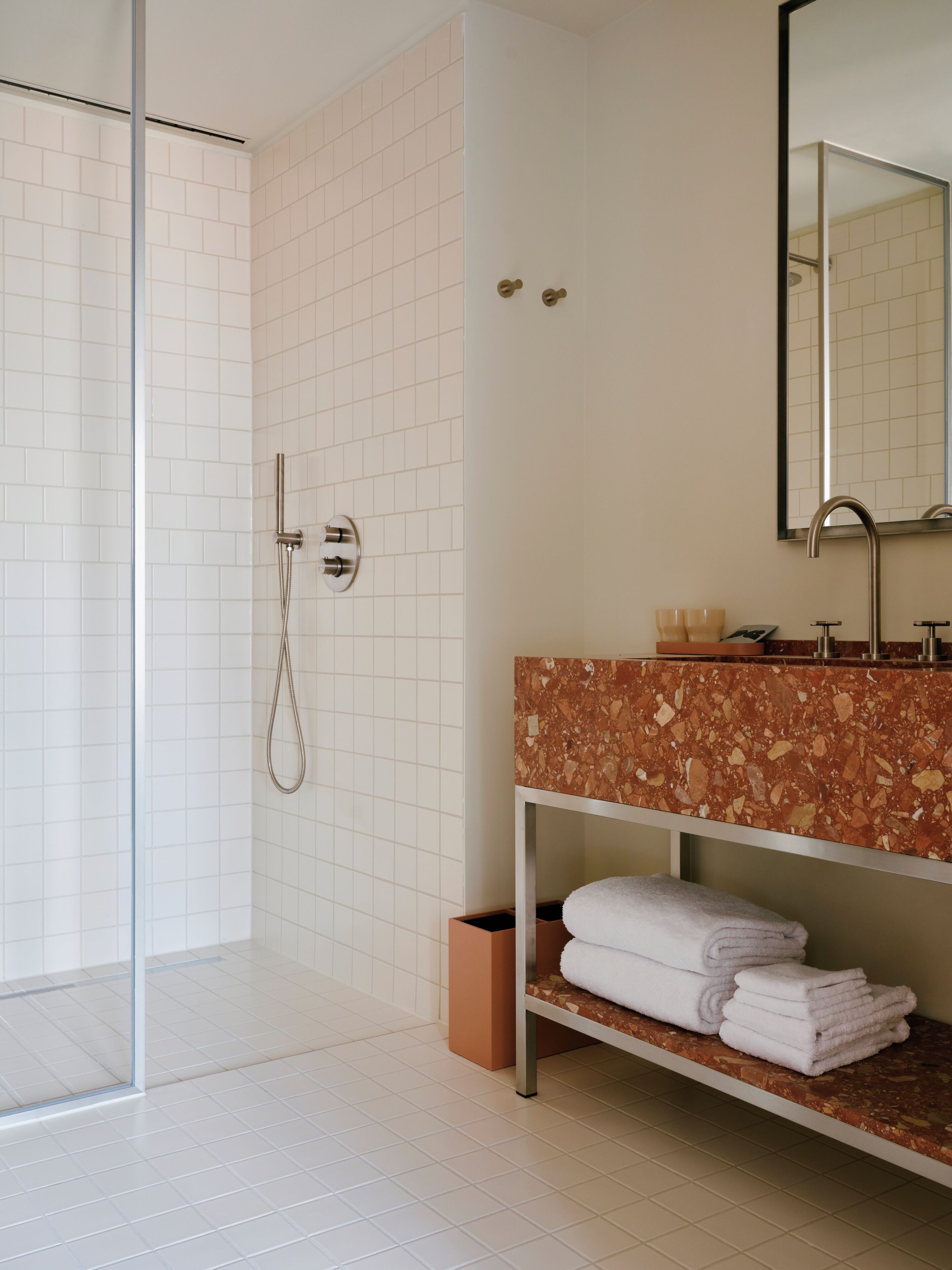 A modern bathroom with a glass shower enclosure, a marble vanity, and a mirror above the sink.
