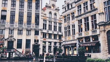 A historic square with ornate buildings, cobblestone pavement, and a café.