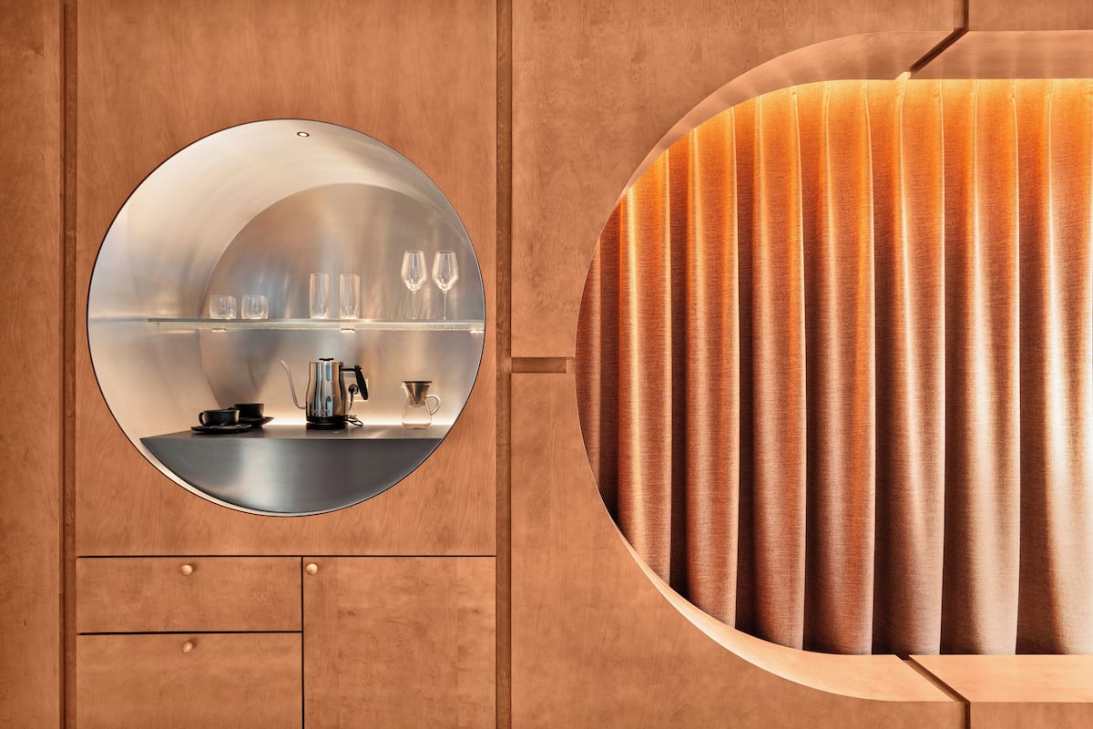 Un baño moderno con un espejo redondo, muebles de madera y un tocador curvo.