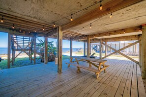 Une terrasse en bois avec des tables de pique-nique donnant sur une plage.