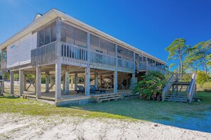 Une maison de plage à deux étages, dotée d’un porche couvert et d’un escalier menant à l’étage supérieur.