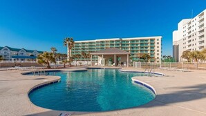 Un hotel con una piscina grande, varios balcones y un edificio central con zona cubierta.
