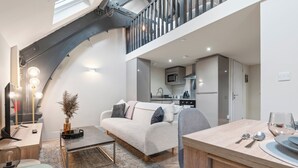 A modern loft-style apartment with a living area, kitchenette, and dining space.