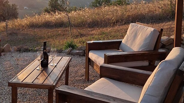An outdoor seating area with a wooden table, two cushioned chairs, and a bottle of wine. - Newly renovated apartment,  ideal for relaxing, nature lovers and walkers  

 (Abruzzo)