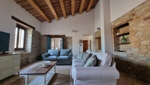 A spacious living area with a stone wall, wooden ceiling beams, and two sofas. - Newly renovated apartment,  ideal for relaxing, nature lovers and walkers  

 (Abruzzo)