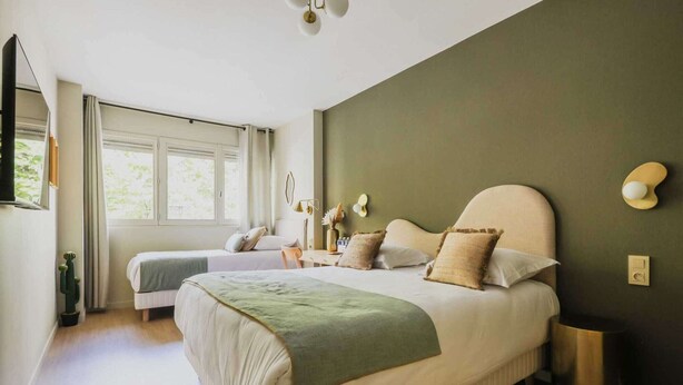 A bedroom with a large bed, a smaller bed, a bedside table, a lamp, and a window with curtains. - Modern "Green Suites" residence - Meudon/Vélizy (Meudon)