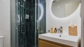 A modern bathroom with a glass-enclosed shower, a white sink with toiletries, and a wooden cabinet. - Modern "Green Suites" residence - Meudon/Vélizy (Meudon)
