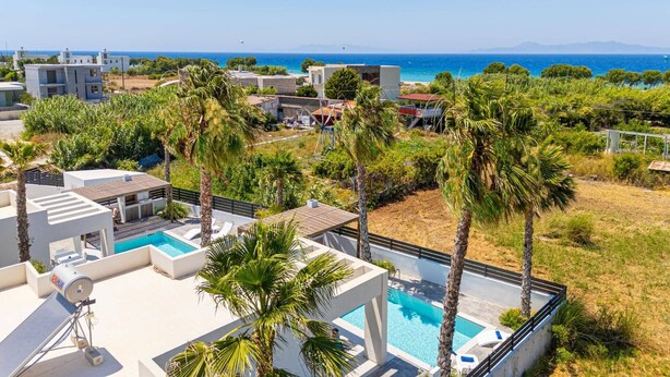 Ein modernes Resort mit Pool, Palmen und Meerblick.