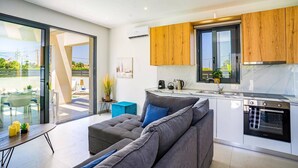 Eine moderne Küche mit Holzausstattung, einem eingebauten Ofen und einem Essbereich mit grauem Sofa und Tisch.