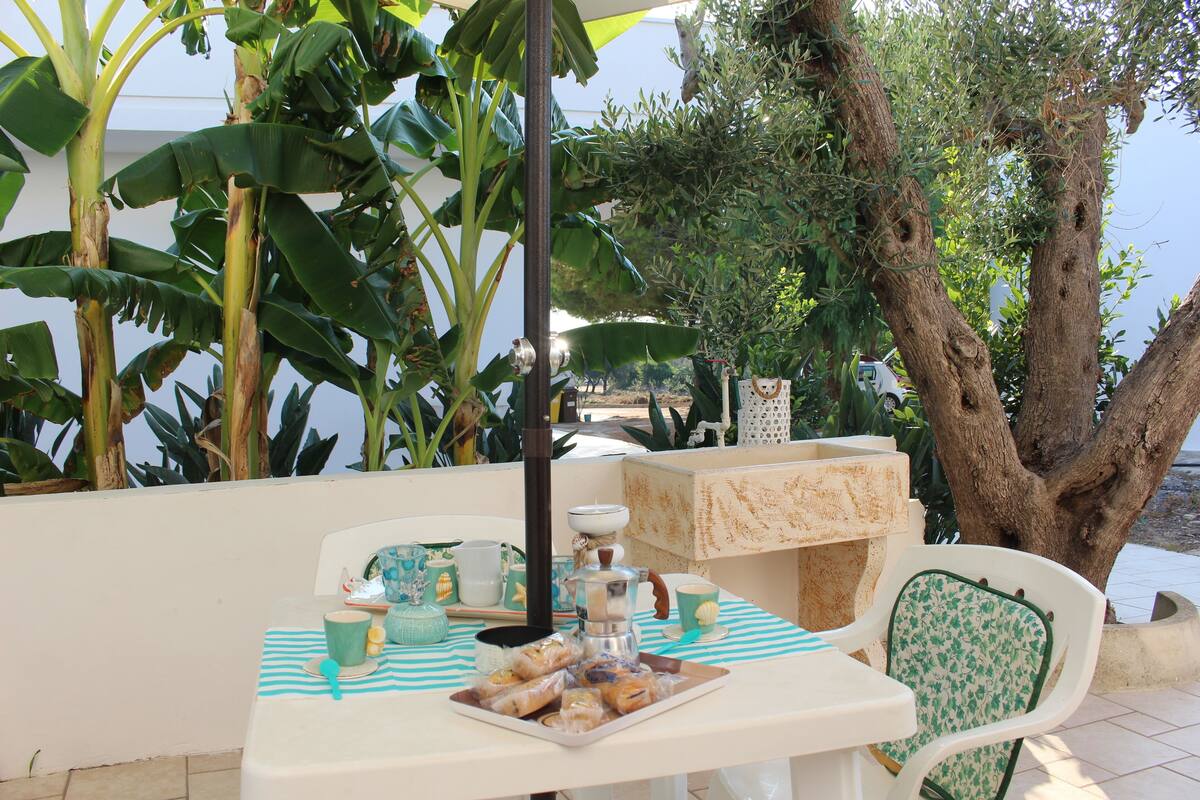 Une table dressée avec un plateau de pâtisseries, une cafetière et une tasse posée sur une nappe à rayures.