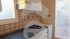 A compact kitchen with a gas stove, a small refrigerator, and a window with a view. - La Riserva dei Felici (Racale)