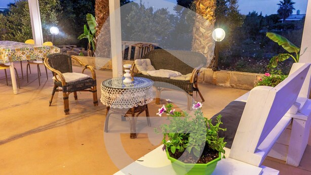 An outdoor patio area with wicker furniture, a round table with a decorative centerpiece, and potted plants. - La Riserva dei Felici (Racale)