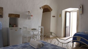 A bedroom with a bed, a small table, a chair, a desk with a chair, a wardrobe, and a door leading to another room. - La Riserva dei Felici (Racale)