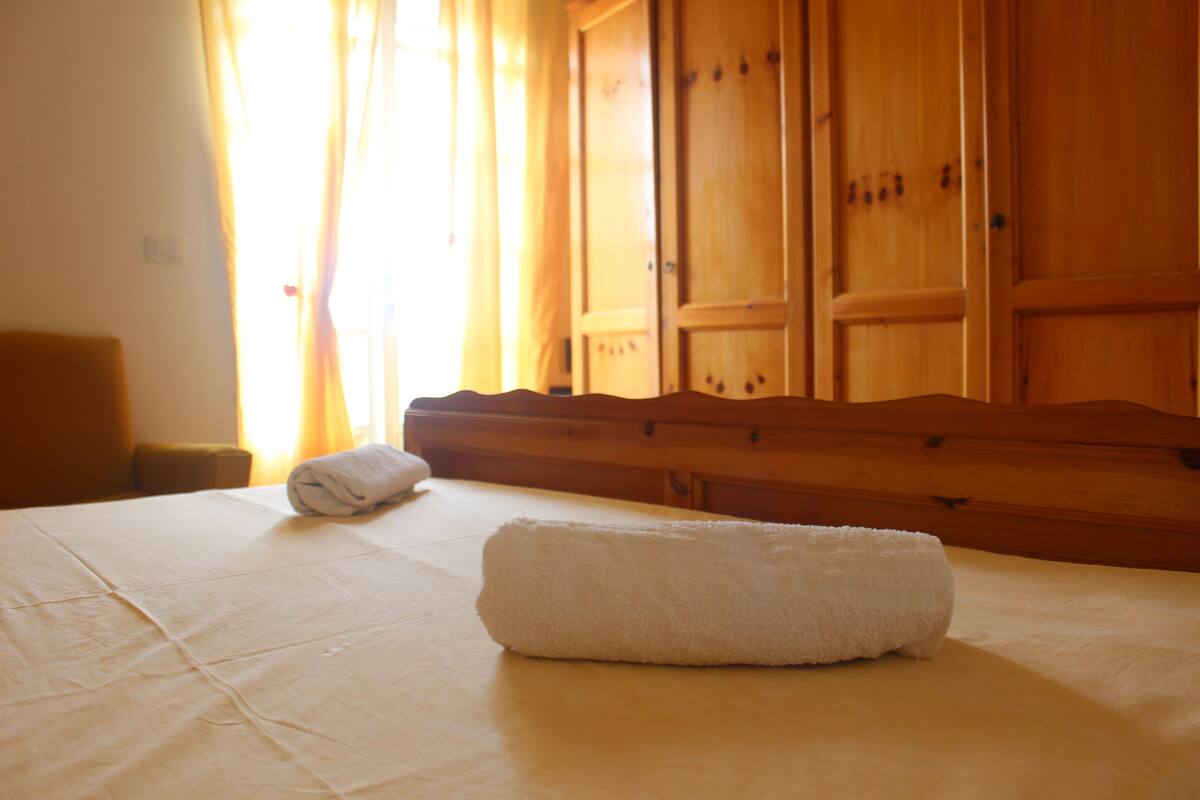 Une chambre d’hôtel avec un lit, une armoire en bois et une fenêtre avec des rideaux.