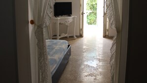 A bedroom with a bed, a small table with a television, and a door leading to a balcony. - La Riserva dei Felici (Racale)