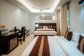 A hotel room with a bed, desk, chair, and a ceiling fan.