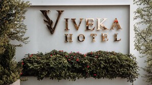 A sign for Viveka Hotel with a decorative letter design and a planter with greenery below. - Viveka Hotel Colombo (Colombo)