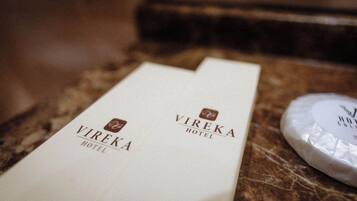Two white Vireka Hotel name cards on a marble surface with a white object nearby.