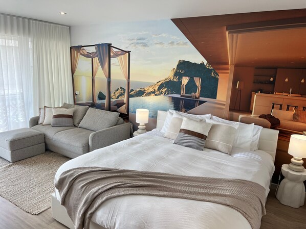 A hotel room with a bed, a sofa, a view of a mountainous landscape, and a pool.