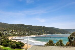 A coastal landscape with a beach, ocean, and hills.