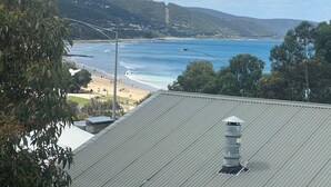 A coastal view with a beach, ocean, and hills in the background. - Bay View Motel - Sunrise (Lorne)
