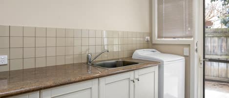 Eine Küche mit integriertem Spülbecken, weißen Schränken und einem Fenster mit Jalousien.