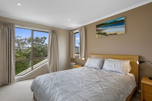 Ein Schlafzimmer mit einem großen Bett, einem Nachttisch, einer Lampe und einem Bild an der Wand.