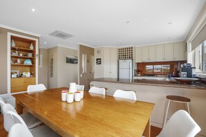 Eine moderne Küche mit einer zentralen Kochinsel, weißen Schränken und einem Essbereich mit einem Holztisch und weißen Stühlen.