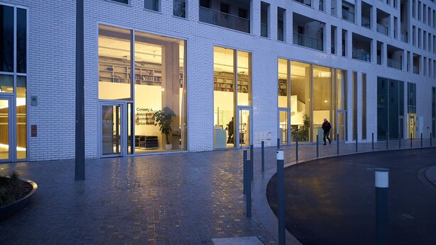 A modern building with large glass windows, a brick facade, and a paved entrance area. - Luxury apartment (Lille)