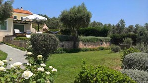 A residential property with a stone wall, a hammock, and a well-maintained garden with roses. - Villa Nerissa, Villa Nerissa (Alonnisos)