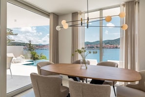 Un espace repas moderne avec une table en bois, six chaises et un luminaire suspendu.