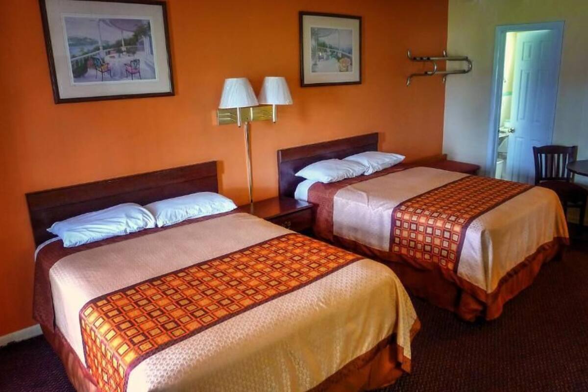 A hotel room with two beds, a small table, and chairs.