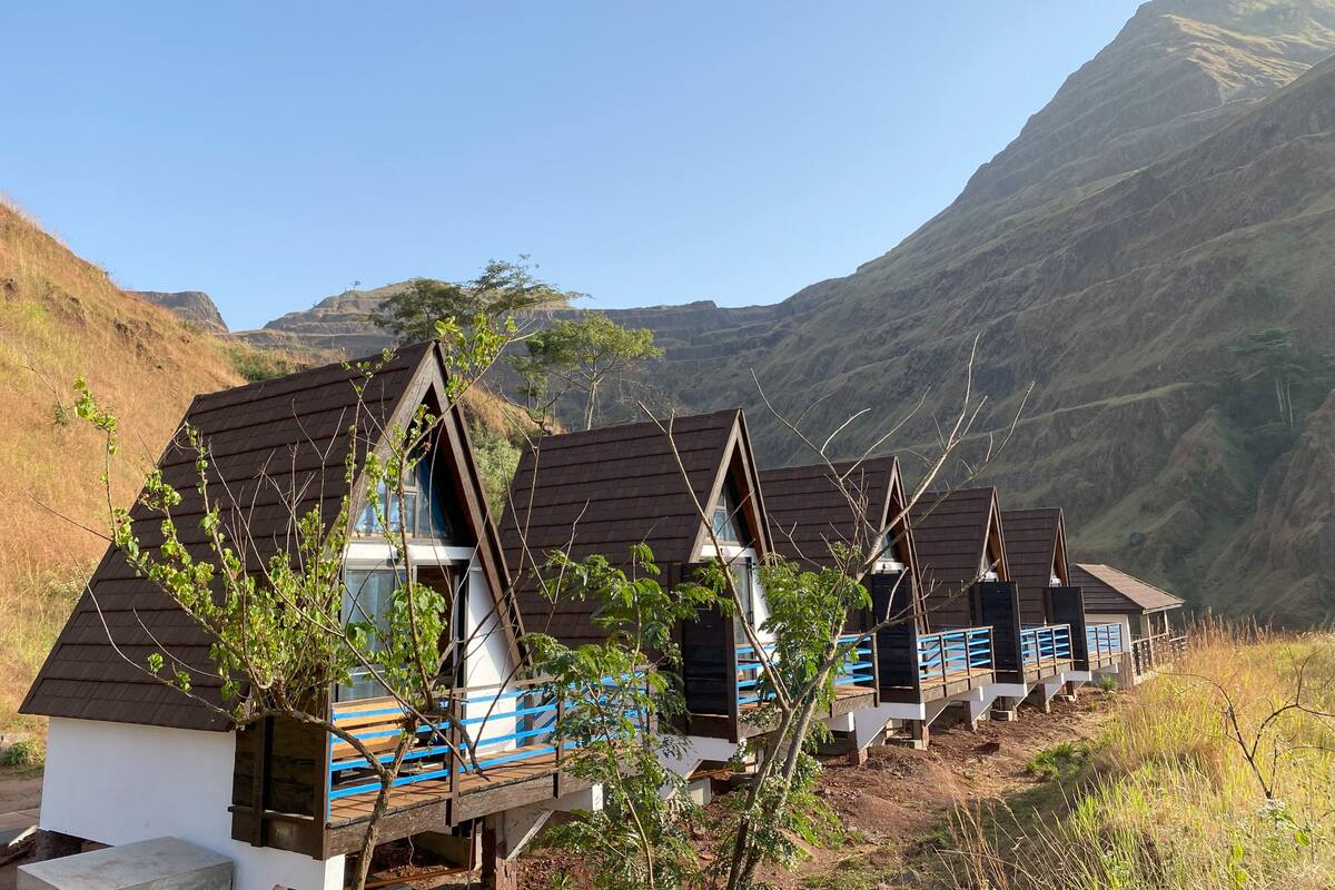 Uma fileira de cabanas de montanha com telhados inclinados, varandas de madeira e janelas.